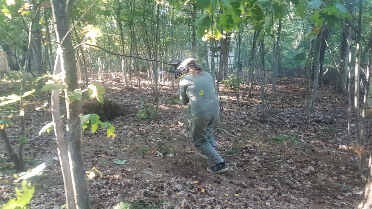 Paintballspielerin rennt durch den Wald während des Paintballduells