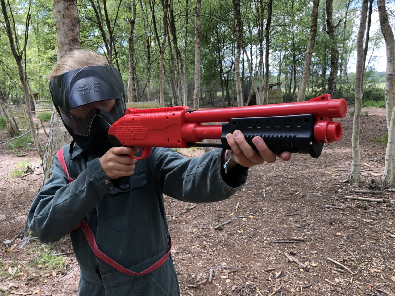 Kind steht im Paintballwald und richtet seine Kinderpaintballgun