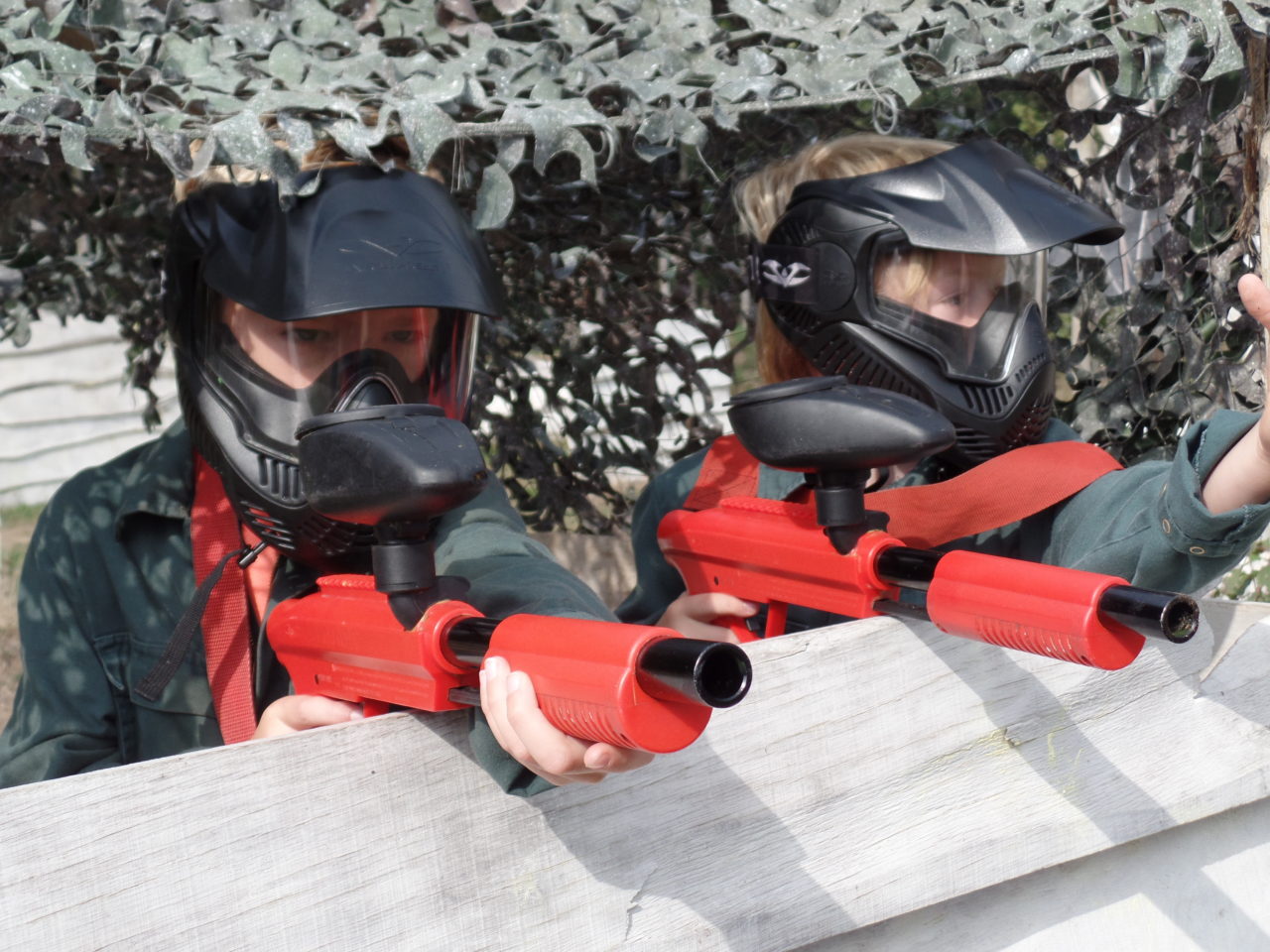 Zwei Kinder sitzen zusammen in Deckung hinter einem Hindernis bei Kinder Paintball