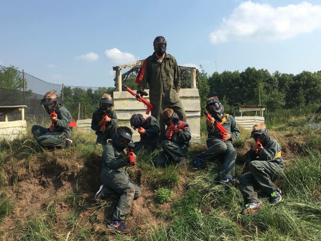 Ein Team von Kindern sitzt auf einer Beule im Paintballfeld für Kinder